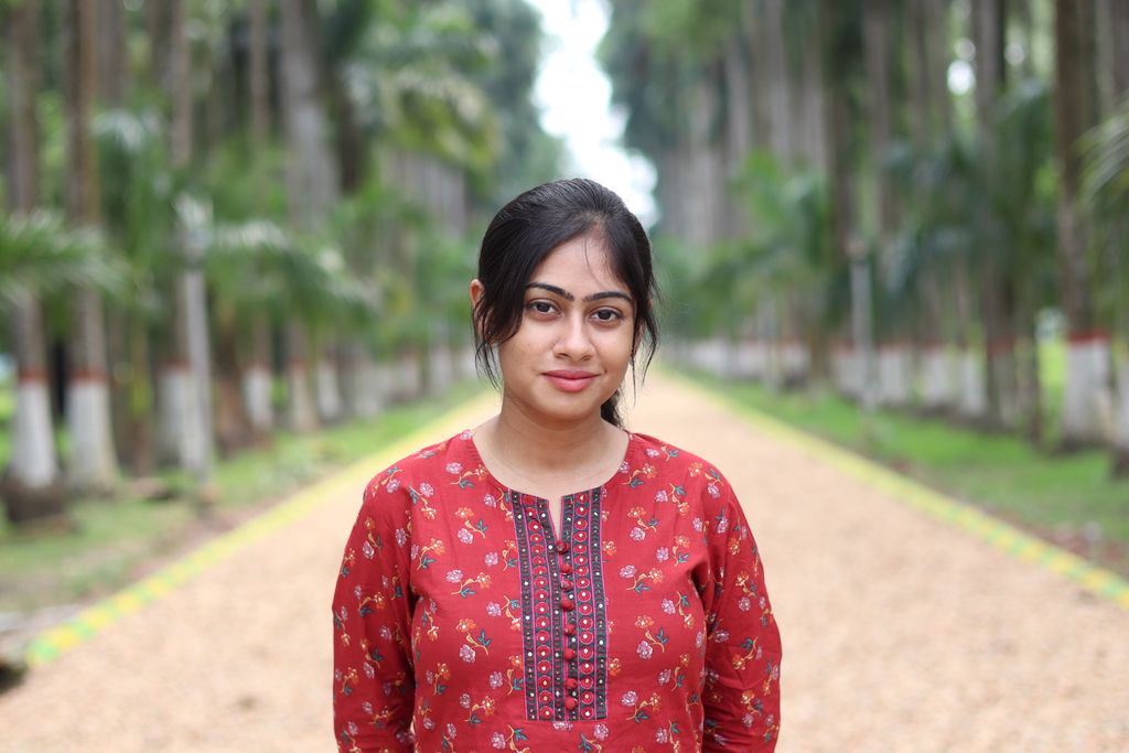 Candid portrait of a young woman in traditional attire with tropical background.